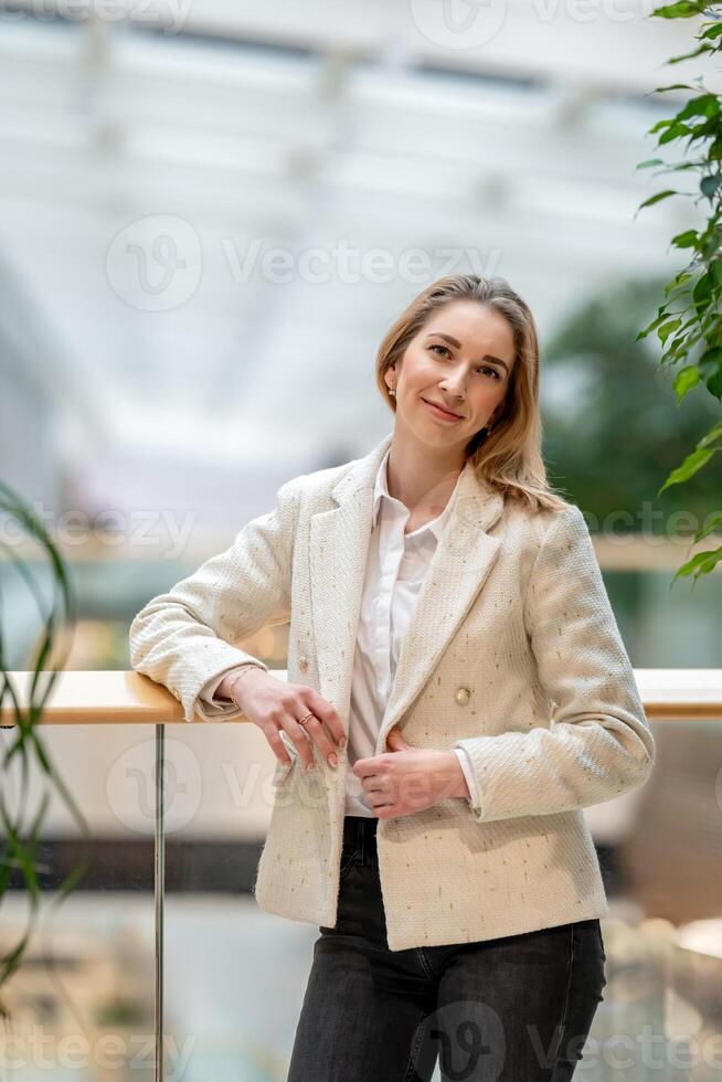 Businesswoman leaning on railing in modern office building photo