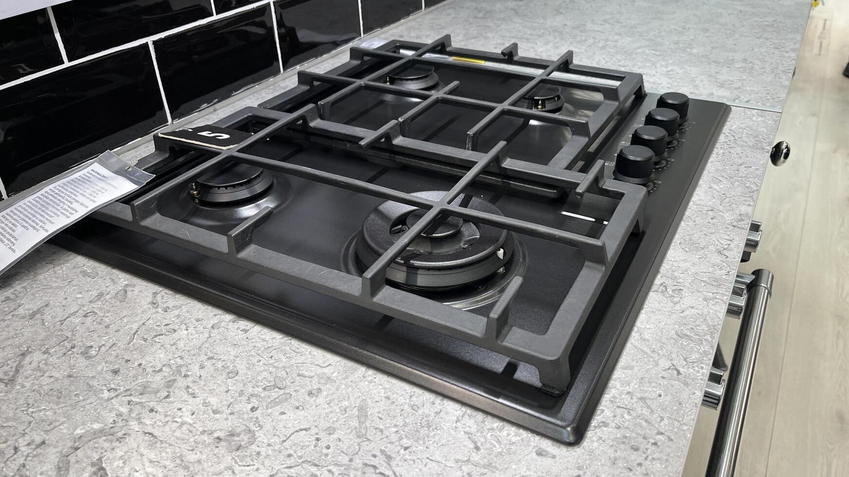 Kaunas, Lithuania. January 24, 2025. A modern gas stove top with multiple burners and control knobs, set against a textured countertop photo