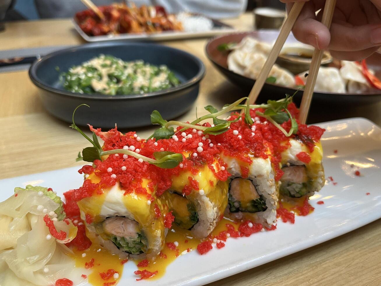 A chopstick take Sushi with salmon, panko tiger prawns, cucumber, unagi sauce, mayonnaise, sesame seeds in Japanese restaurant photo