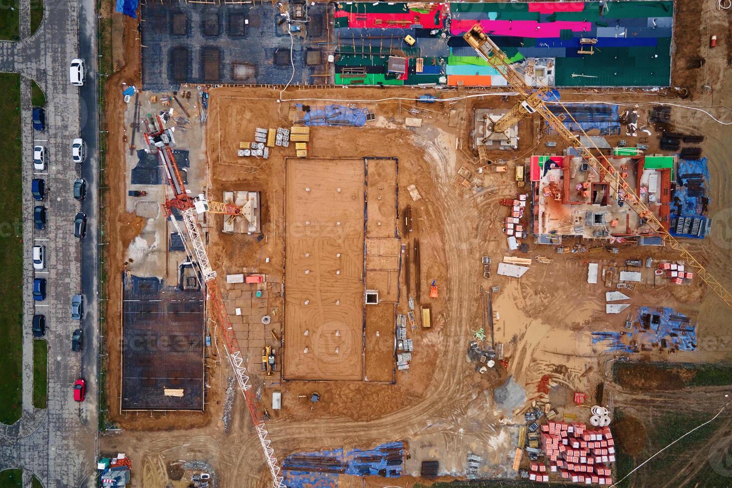 Aerial view of construction site with cranes, foundations and building materials. Residential building under construction. Progress of new development in small town photo