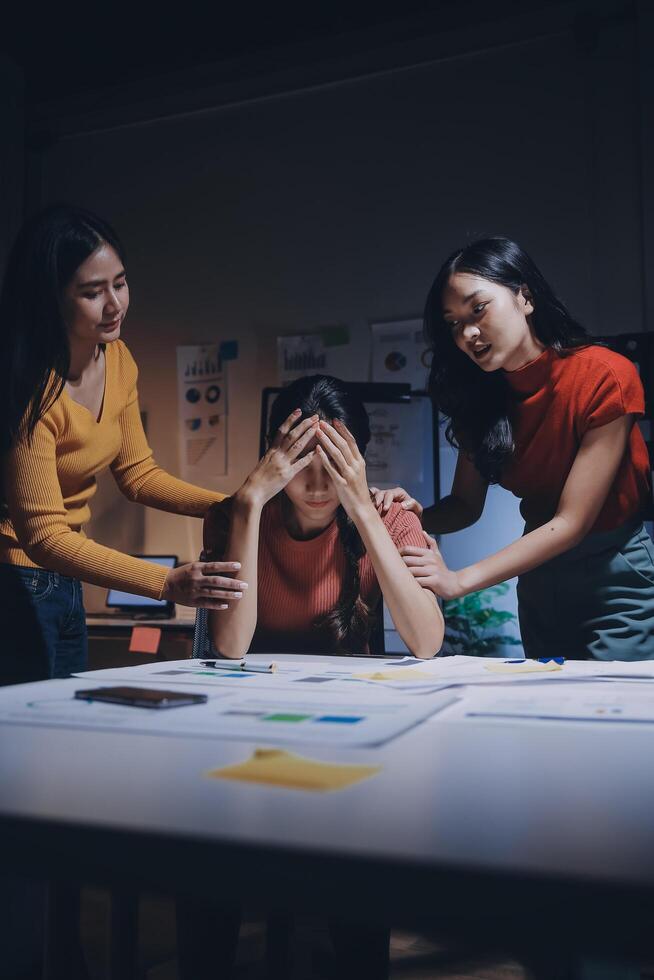 Three women sitting at a table with a man in the background photo