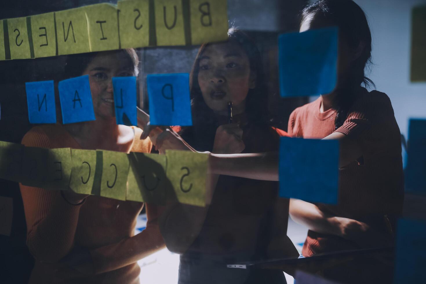 Three women looking at a business plan on sticky notes photo