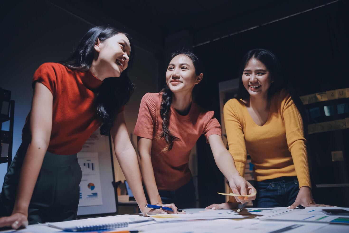 Three women smiling at a table with papers photo
