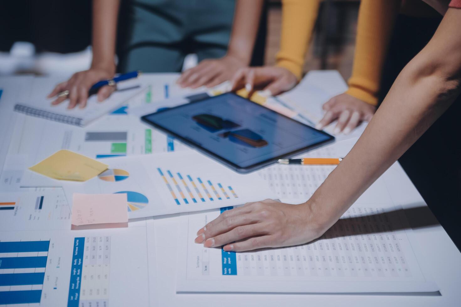 Business people working on a tablet with papers and graphs photo