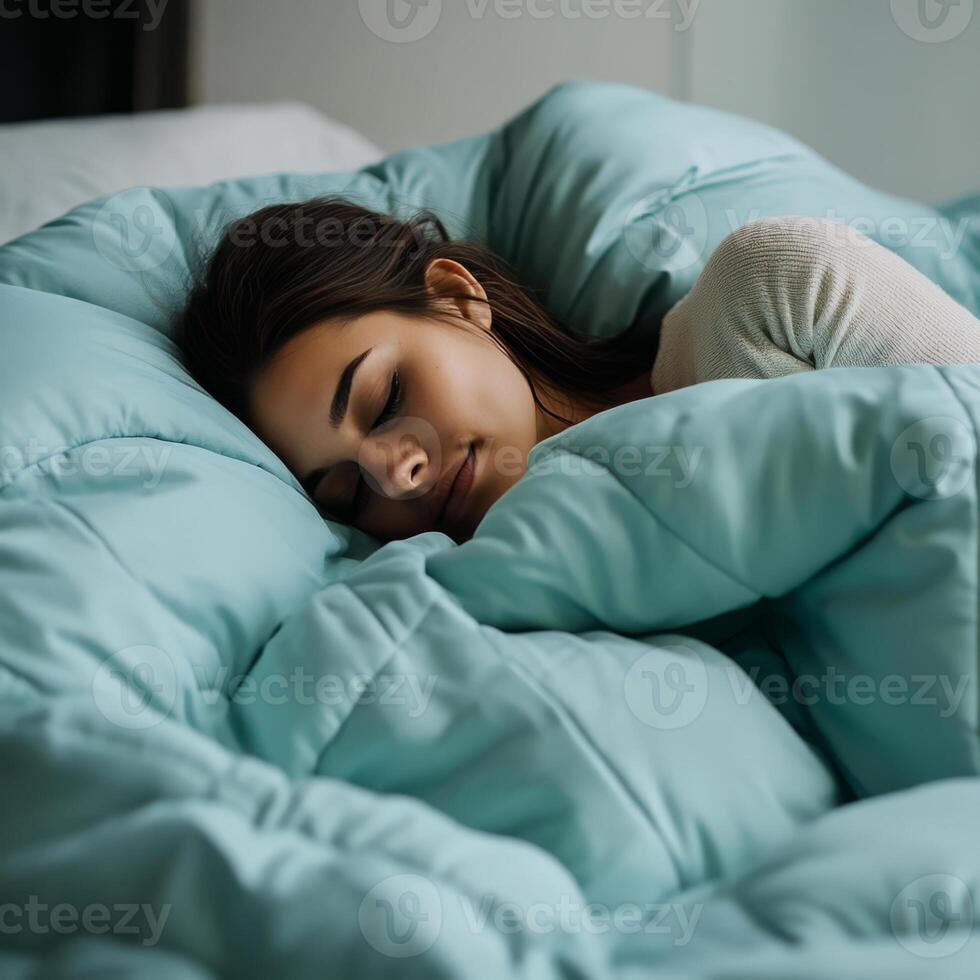 woman sleeping peacefully under cozy aqua blue comforter, exuding tranquility and comfort in serene bedroom setting photo