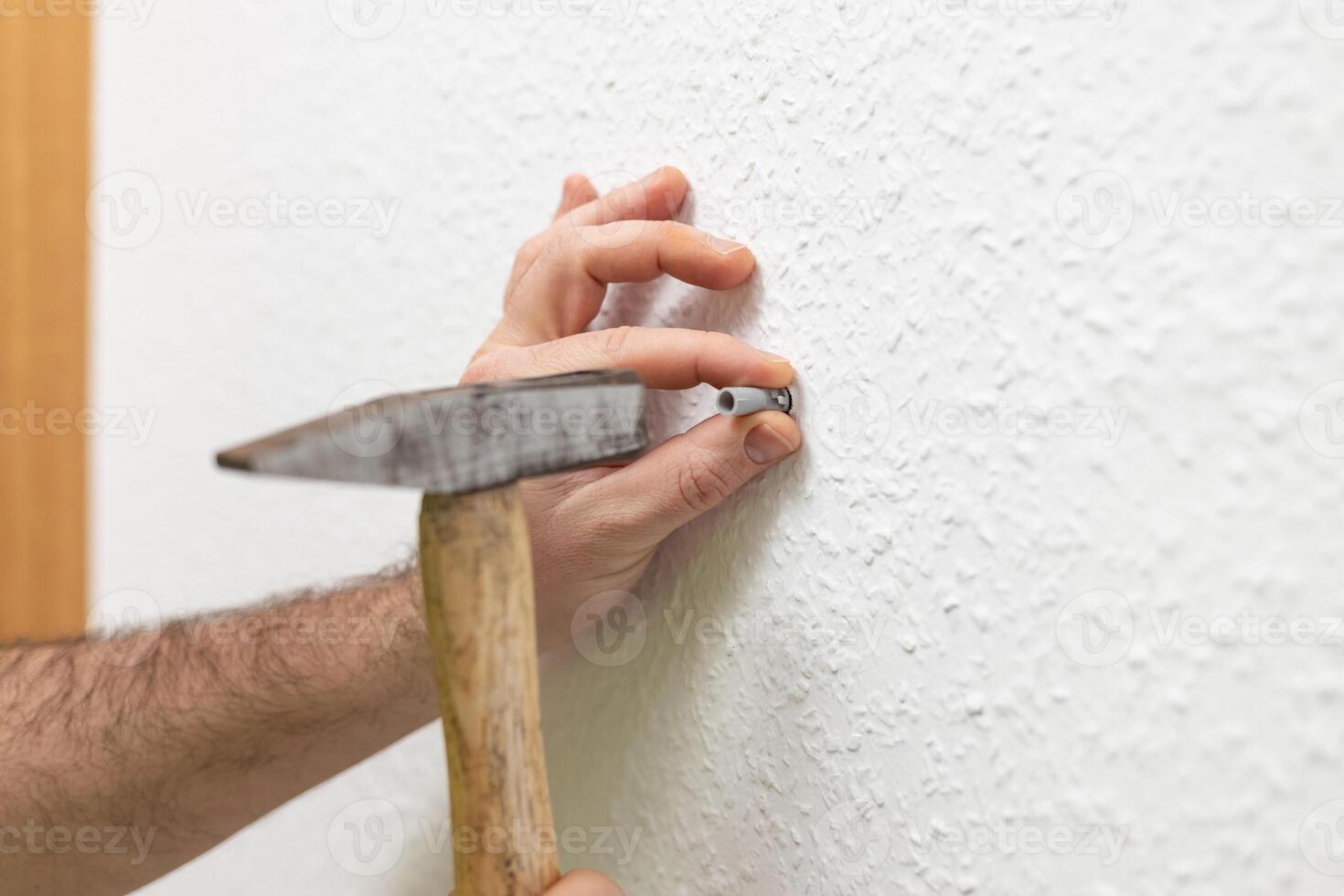 A man uses a hammer to hammer nails. A hammer is the main tool of a builder. High skills in working with a tool do not lead to injuries. Safety concept when working with a hammer photo