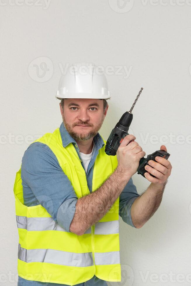 professional tool. builder with a drill at construction site. A drill is one of most versatile tools that is needed at every stage of construction. A tool in hands is an extension of personality photo