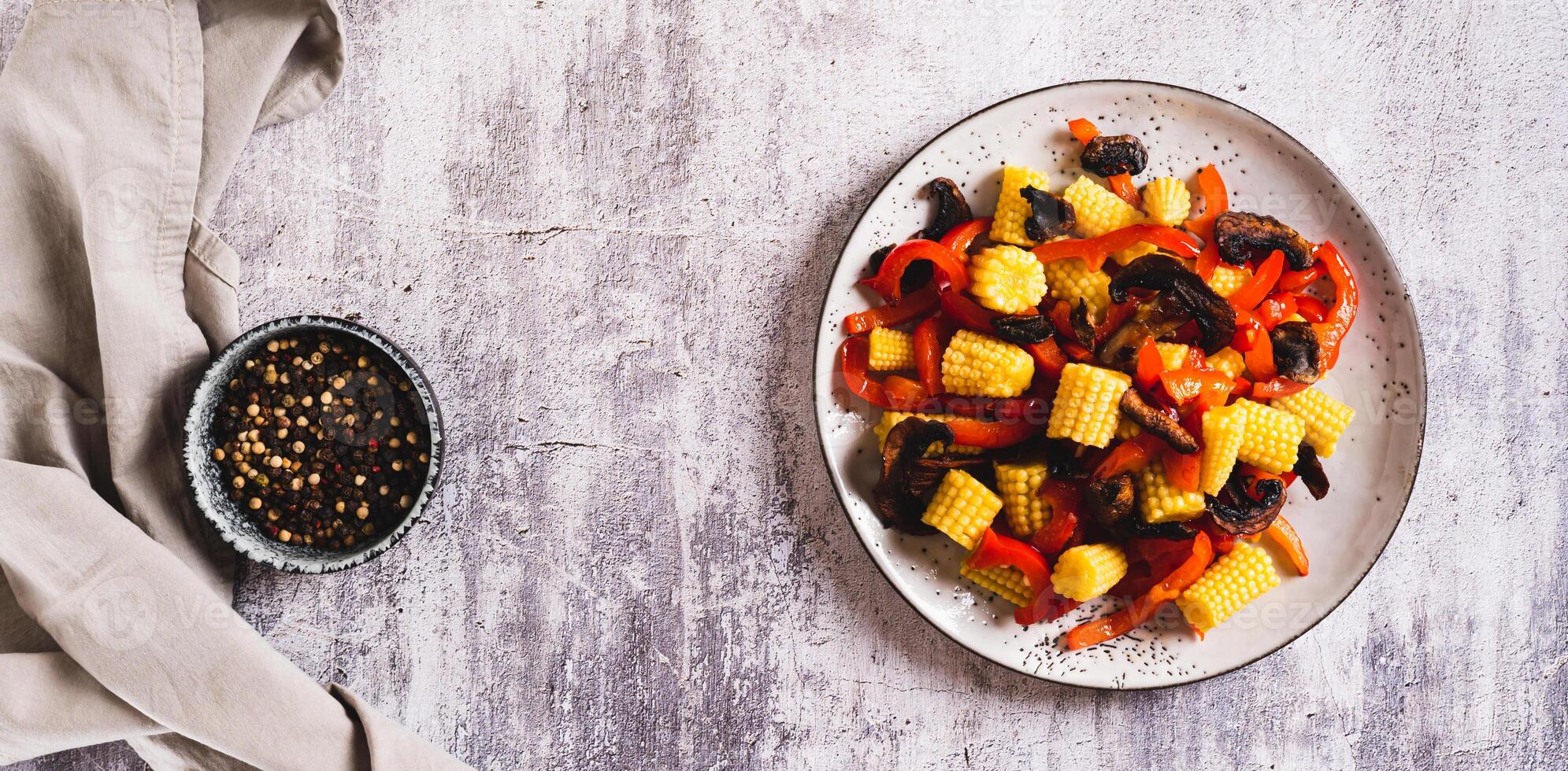 Vegetarian salad with corn cobs, mushrooms and peppers on a plate top view web banner photo