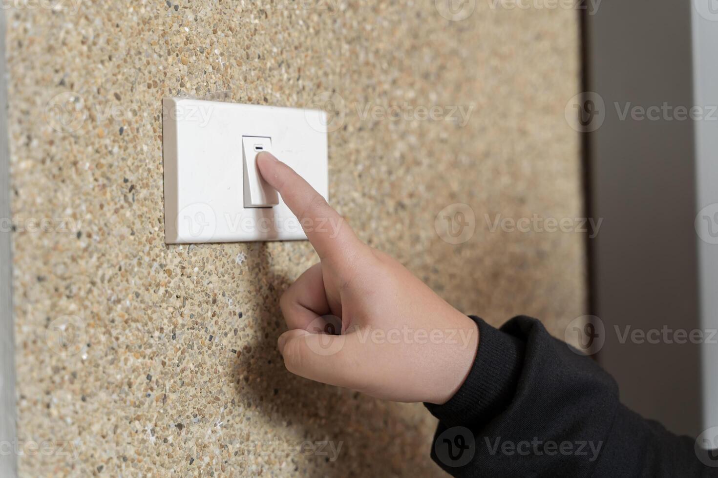 Woman hand pushing light switch at home. A woman turns off the home light switch when she leaves the room. photo