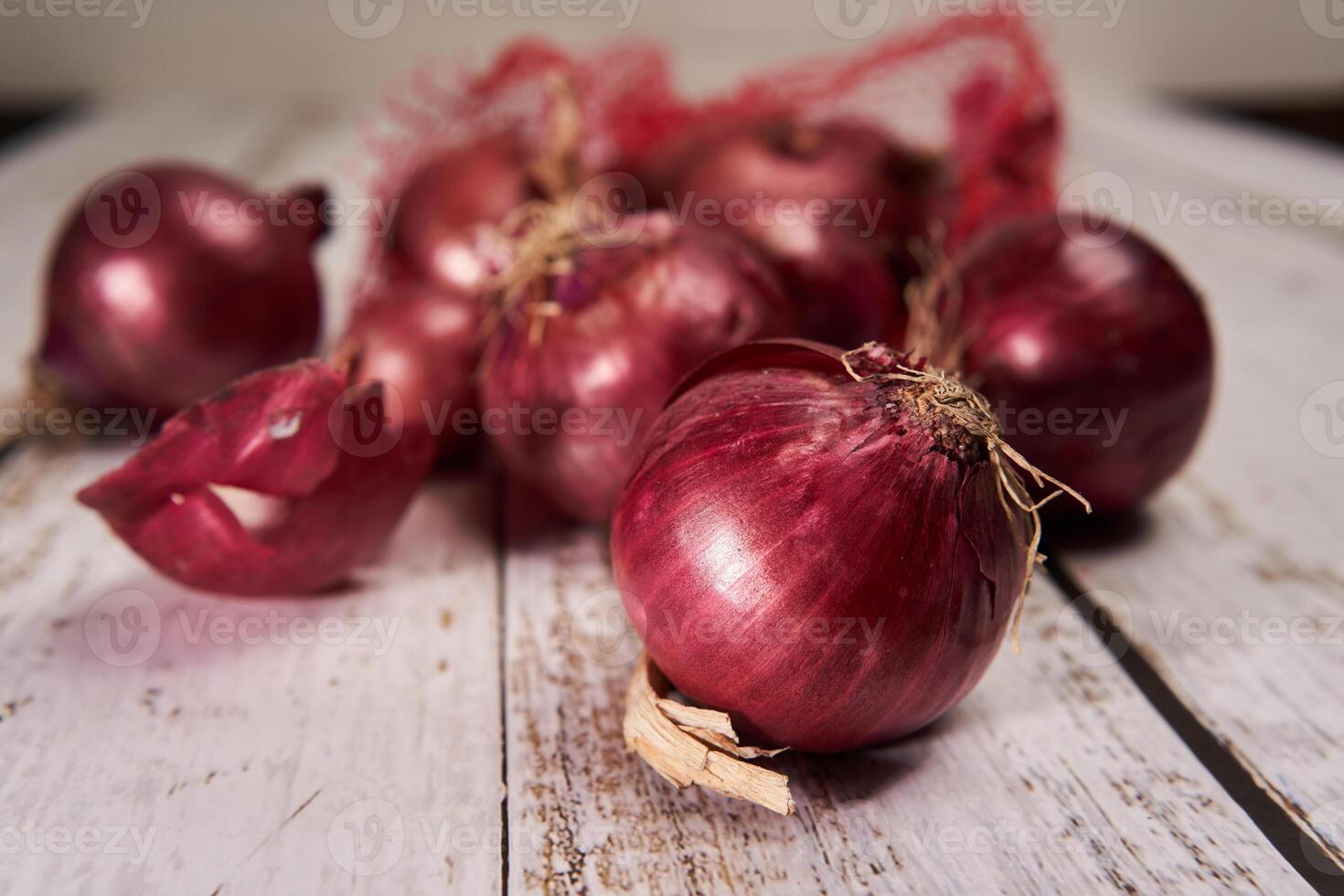 A pile of red onions on a wooden table photo