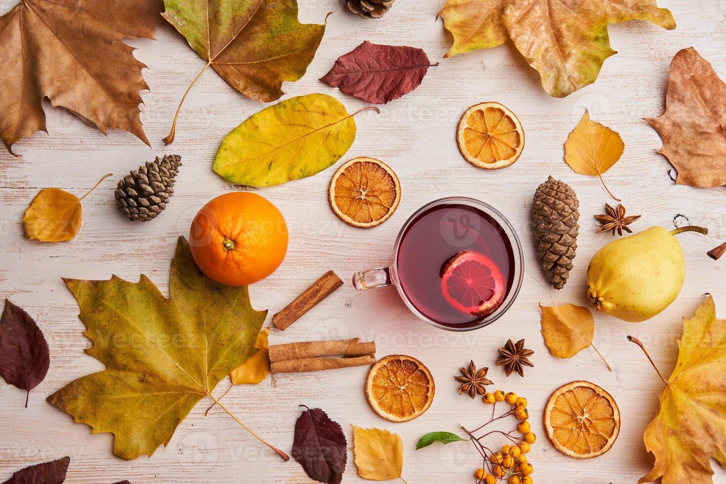 Autumn leaves, oranges, cinnamon, and tea on a white table photo