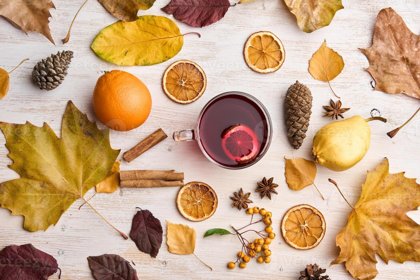 Autumn leaves, oranges, and spices surround a cup of tea photo