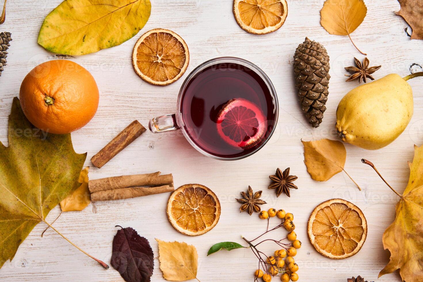 A cup of tea surrounded by oranges, cinnamon and other spices photo