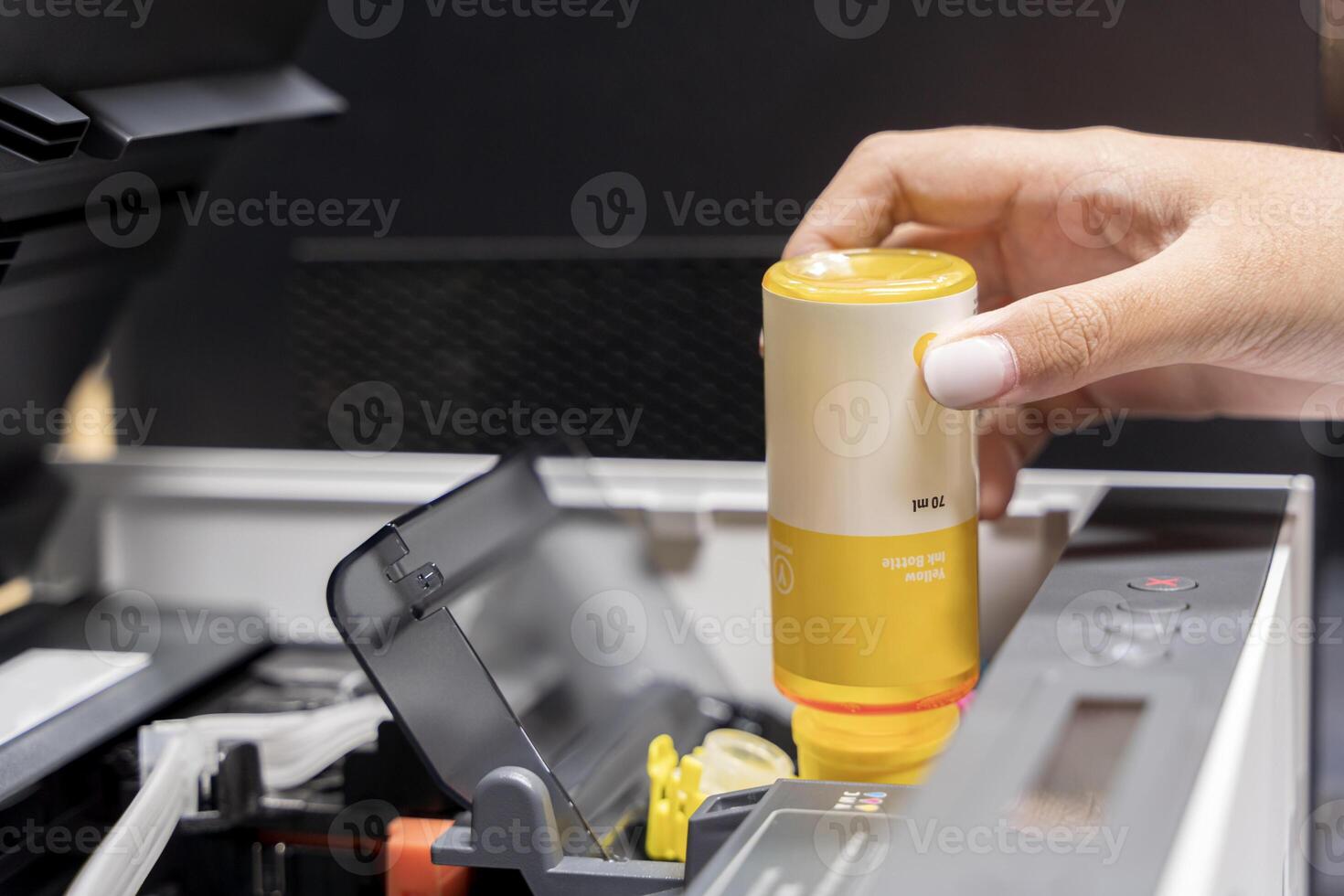 Refill ink tank printer at office. Close up printer cartridge inkjet of color yellow CMYK and repair fix the problem concept. photo