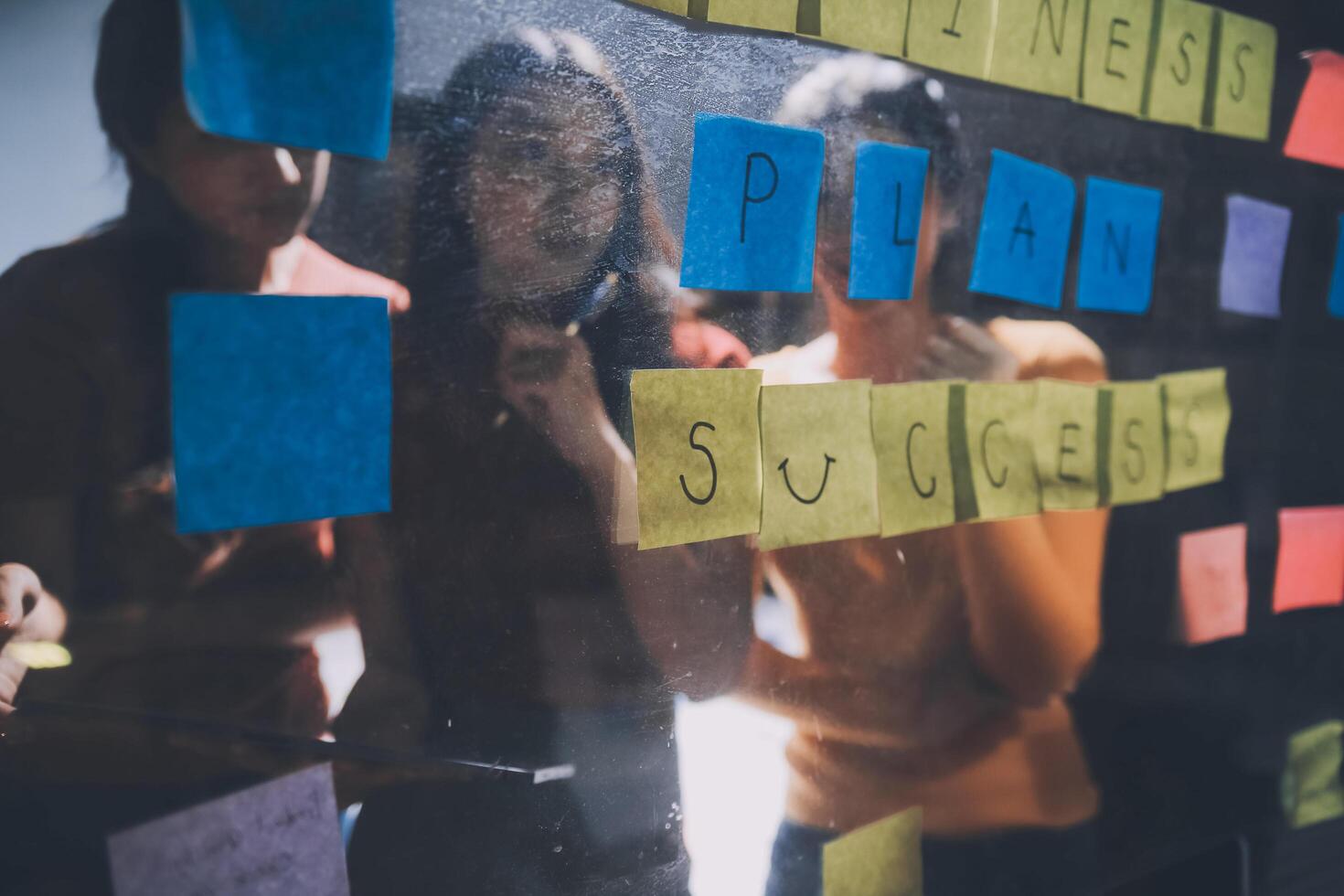 Three people looking at a board with sticky notes photo
