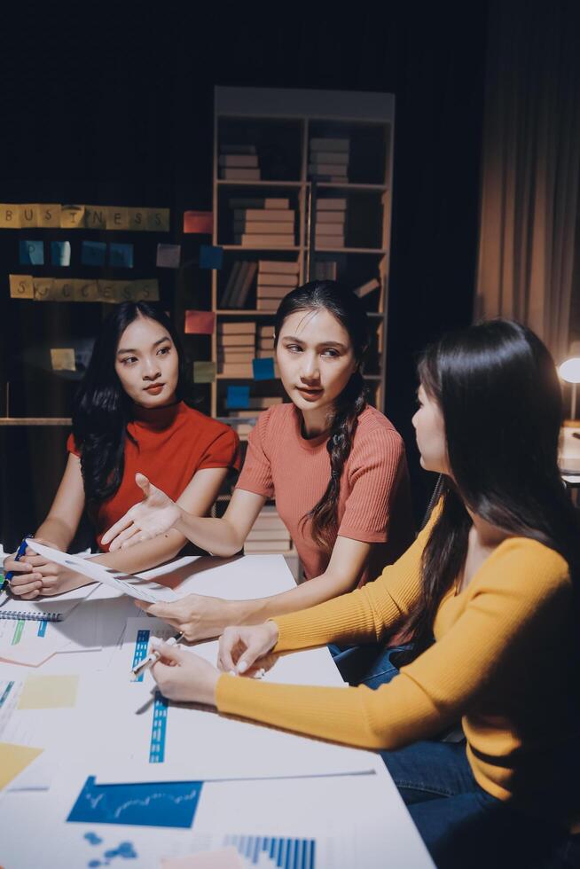 Three young women sitting at a table with papers photo