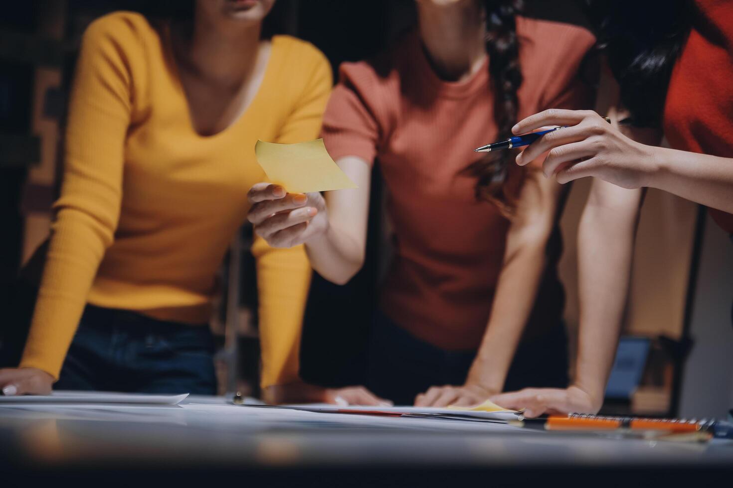 Three women standing around a table with a piece of paper photo