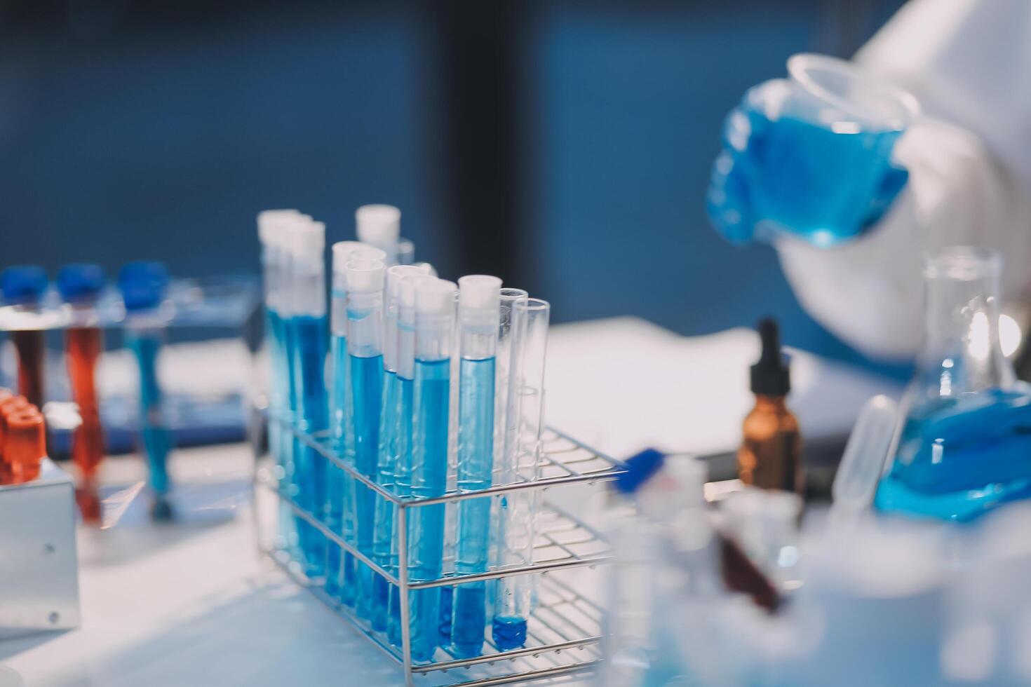 A person in a lab coat is holding a test tube photo