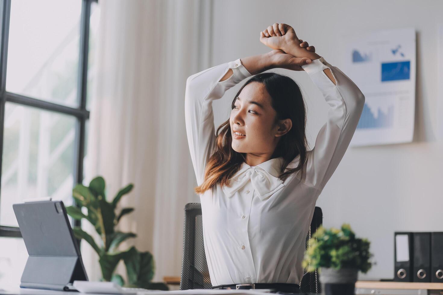 A woman stretching her arms in front of a laptop photo