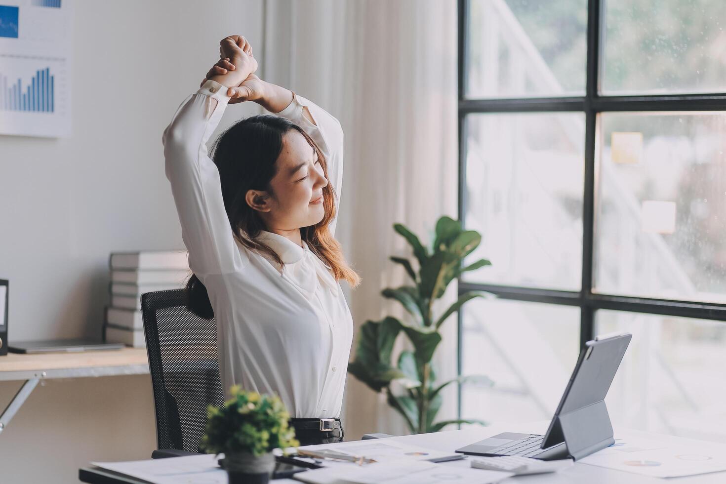 A woman stretching her arms in front of a laptop photo