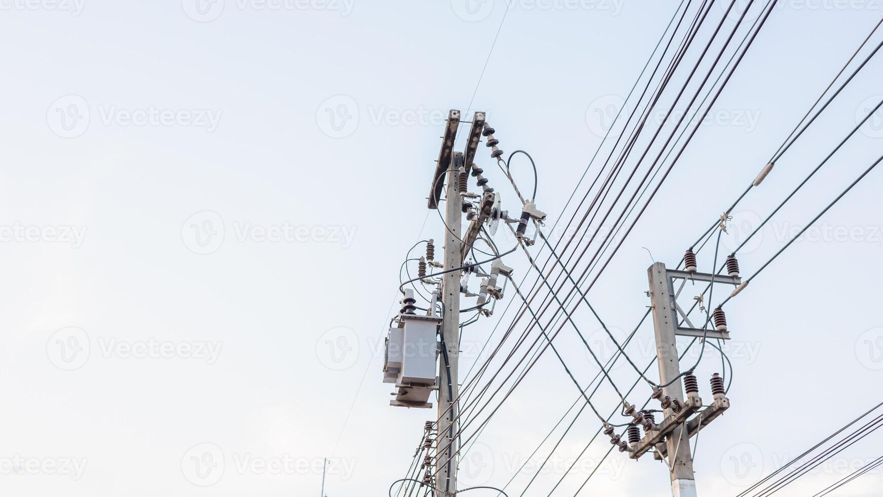 Electrical energy transfer distribution on concrete pole against white sky background, AC high-voltage power transformer, A low angle shot of a power transformer and electrical wires on a metal pole photo