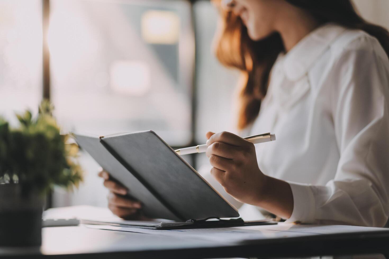A woman is writing on a notepad while sitting at a desk photo
