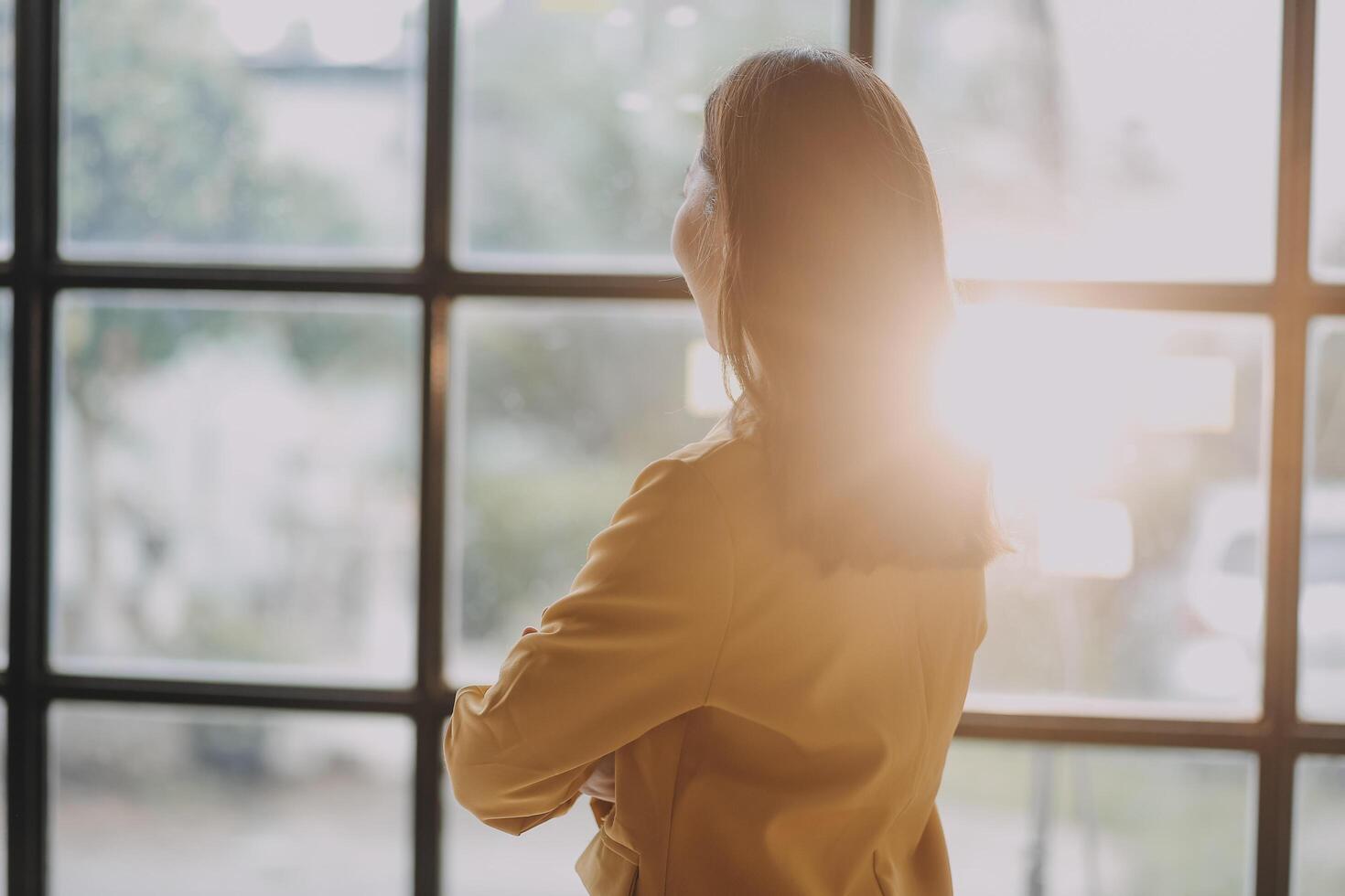 A woman standing in front of a window looking out photo