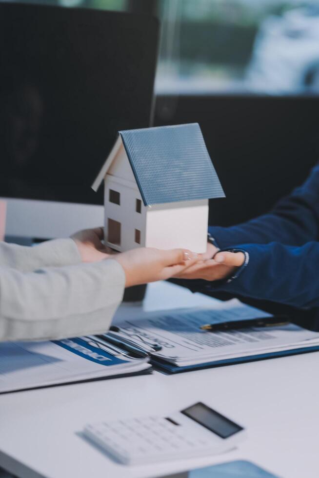 A real estate agent handing a house model to a client photo
