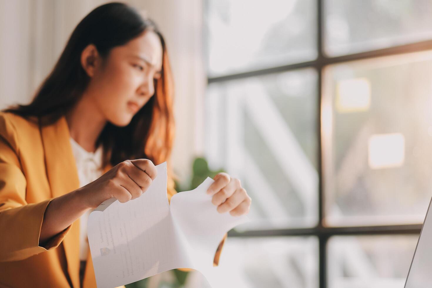 A woman in a yellow jacket is holding a piece of paper photo