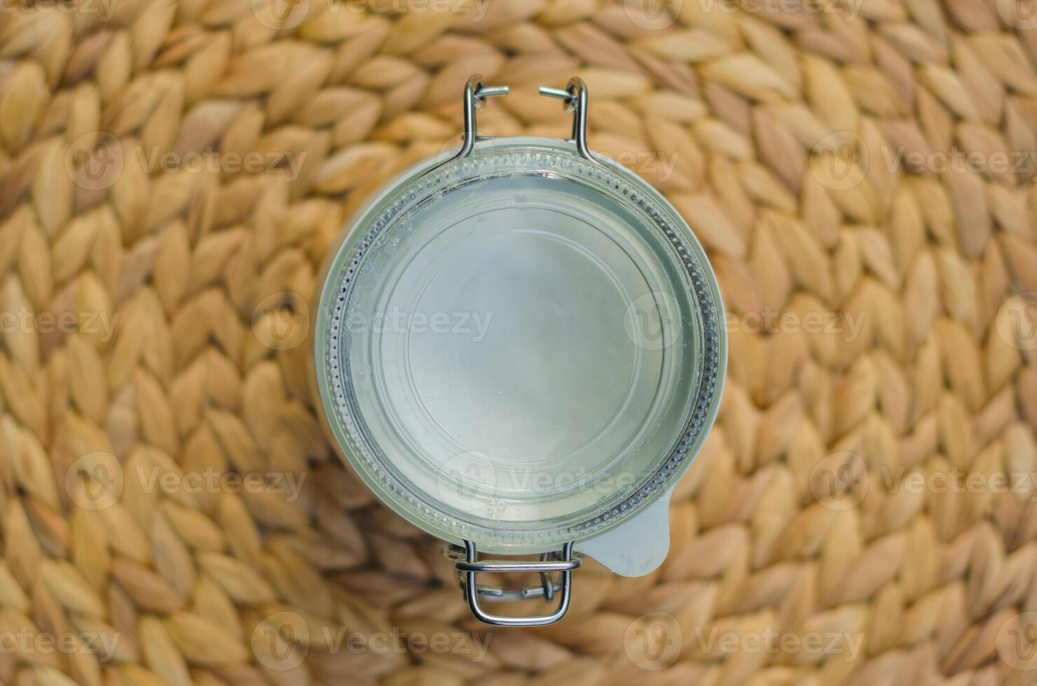 Empty glass jar with metal lid, top-down view, on woven wicker placemat. High quality photo