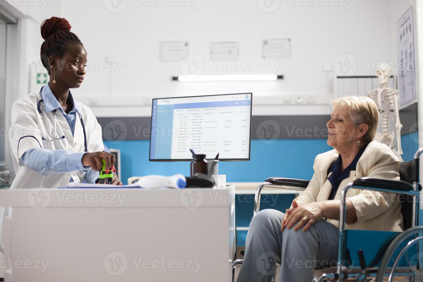 Professional doctor stamps on diagnosis form discussing with elderly woman about treatment plans. Physician stamping prescription document to complete consultation with old female wheelchair user. photo
