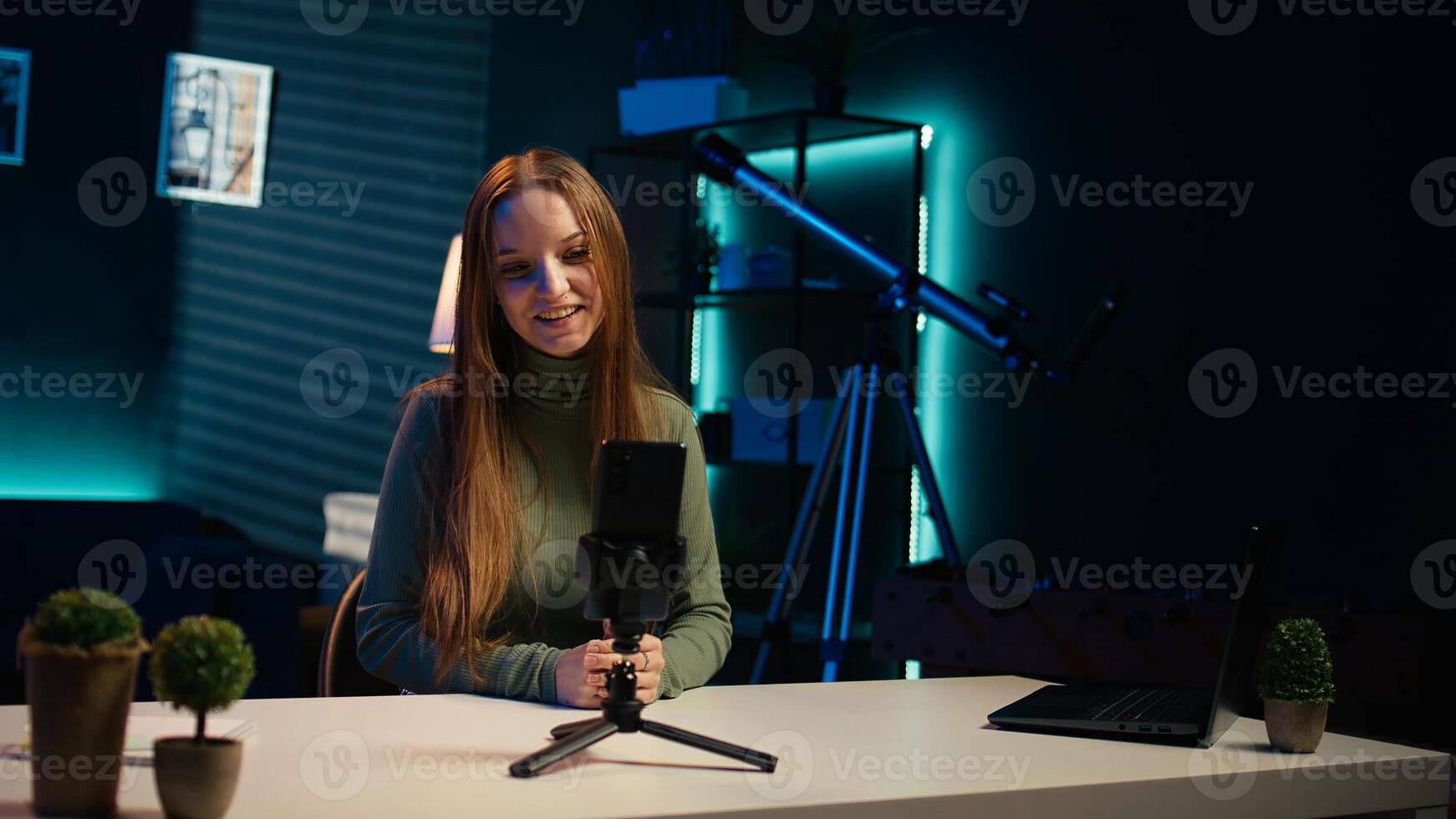 Content creator arriving in studio, using smartphone on tripod to shoot introductory segment for vlog channel. Media star greeting devoted fan community, introducing today subject, camera B photo