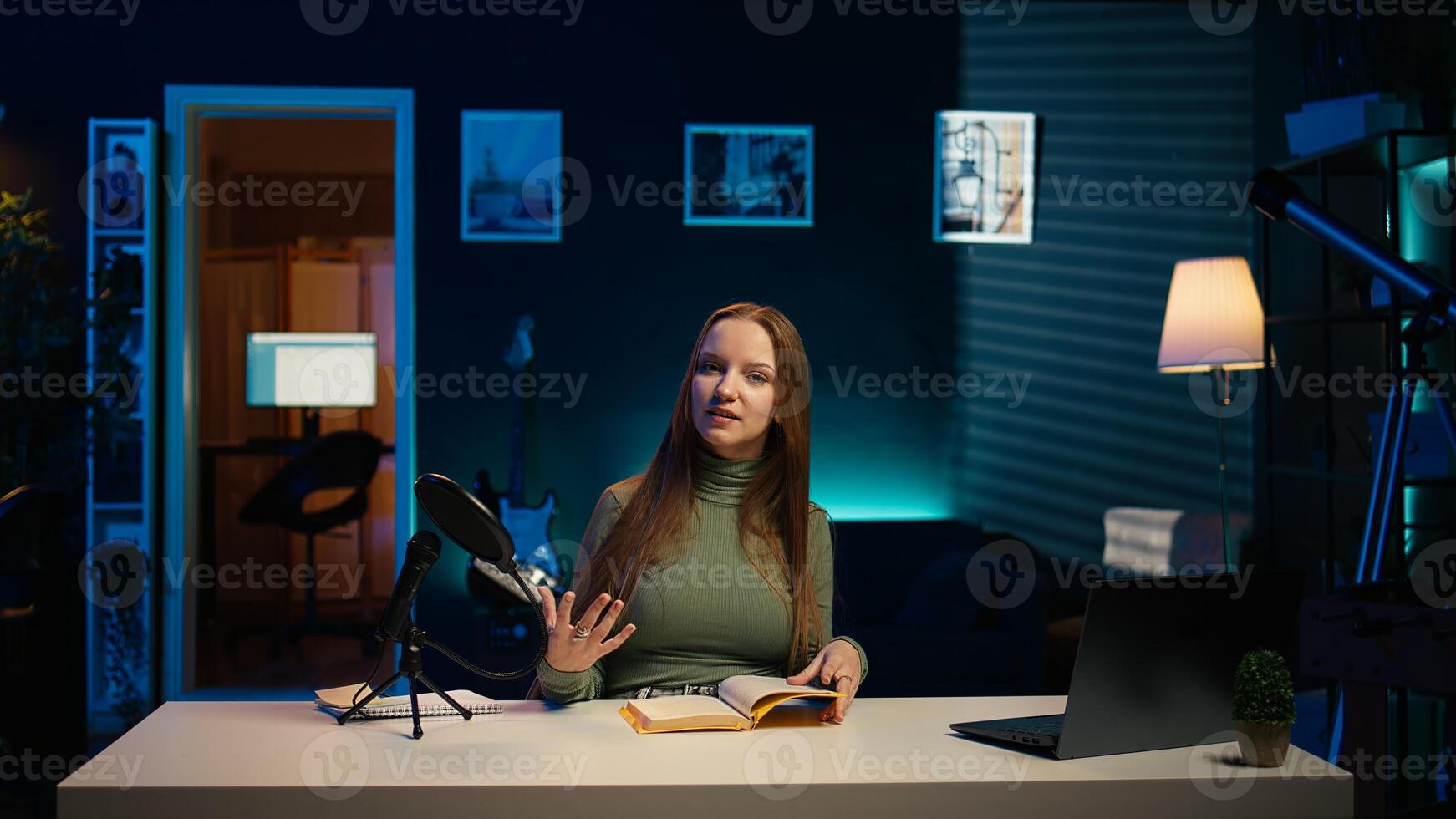 Young girl films review of book, browsing through pages, presenting synopsis to audience. Online star sponsored by publisher to show new novel release to readers, camera B photo