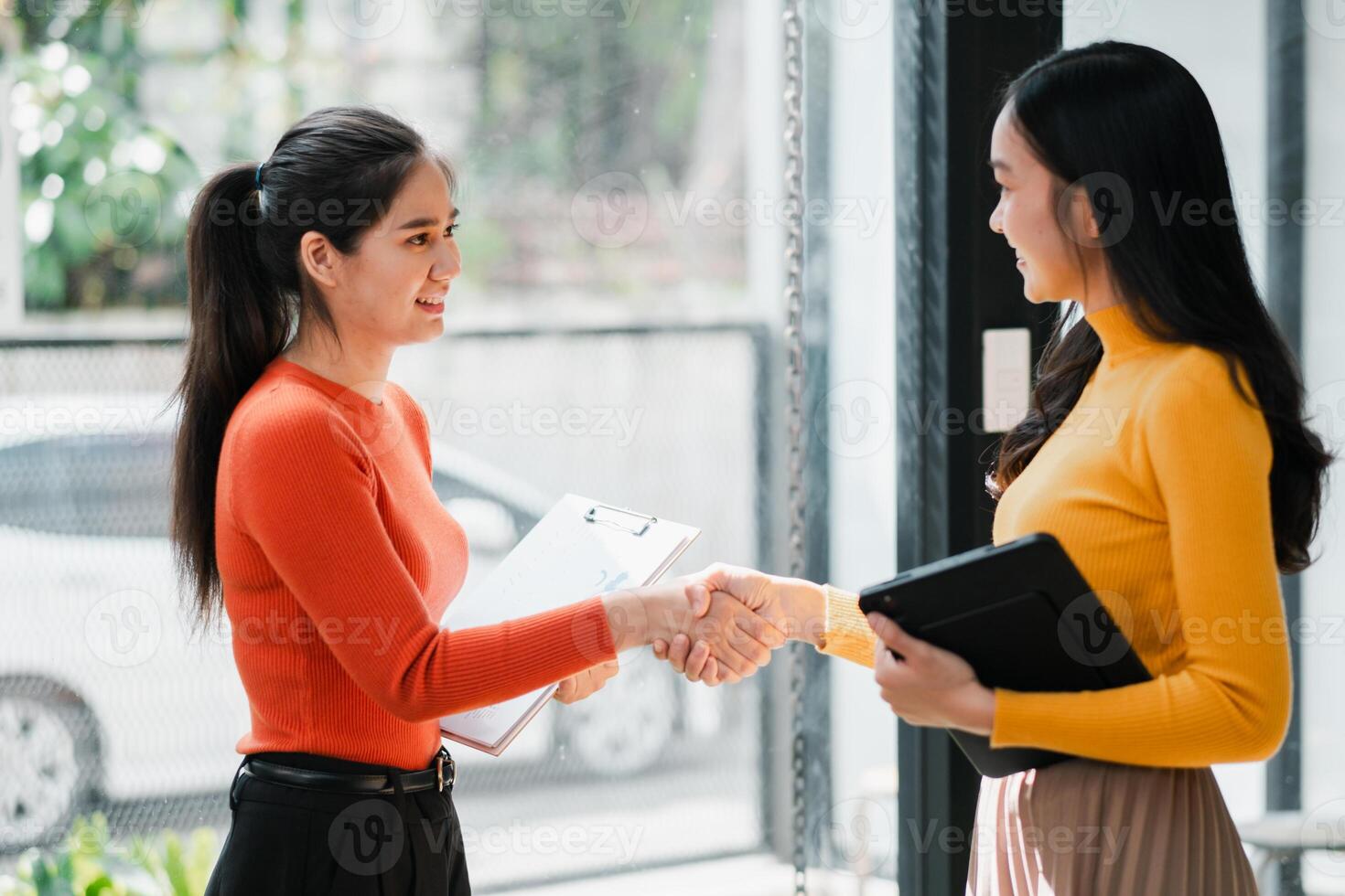 Two women in a modern office shaking hands, symbolizing successful business collaboration and partnership. photo