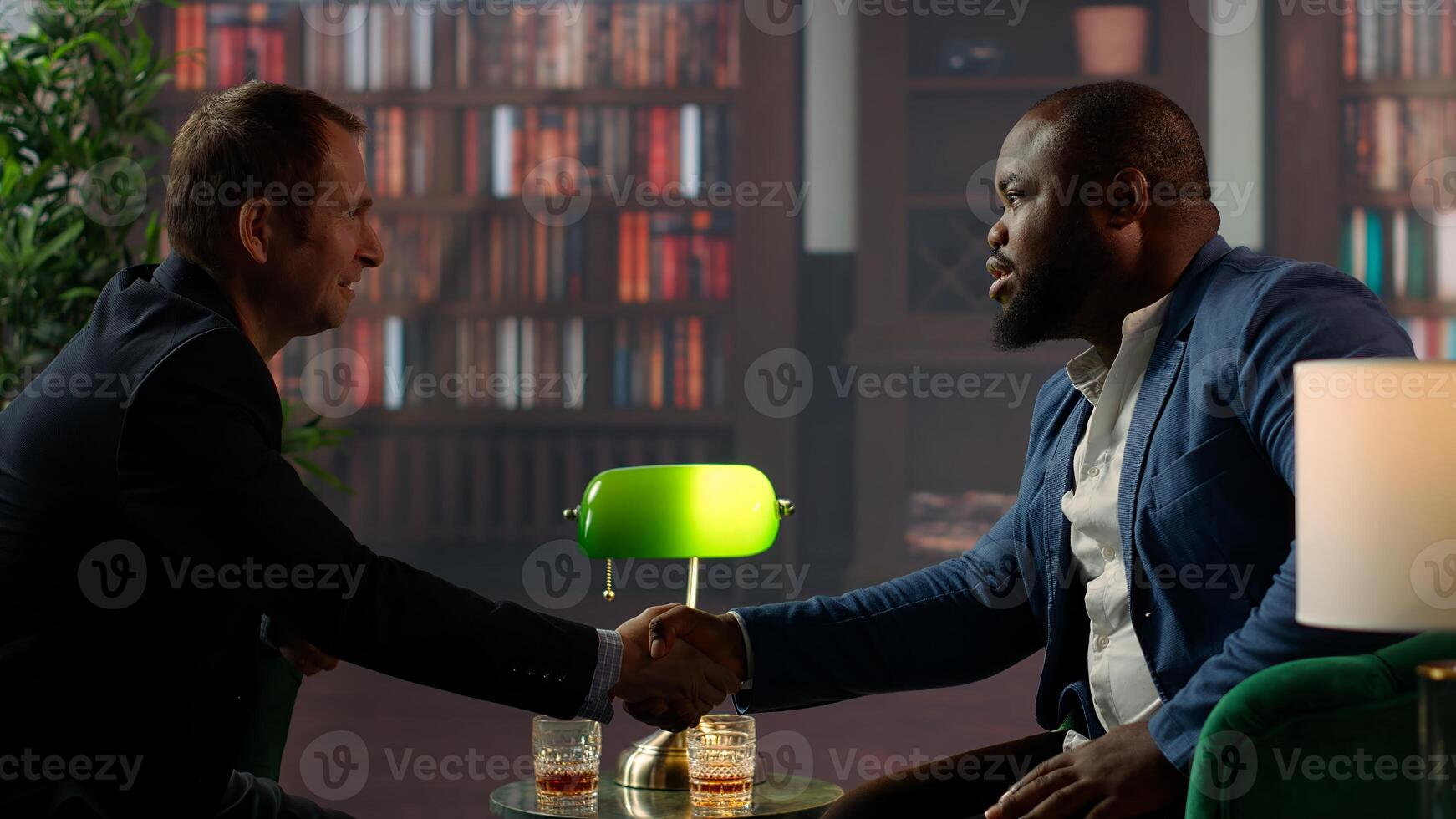 Diverse old money aristocrats shaking hands in agreement to unite their business, striking a deal over whiskey at the elite social club. Upper class gentlemen starting a new alliance. Camera B. photo