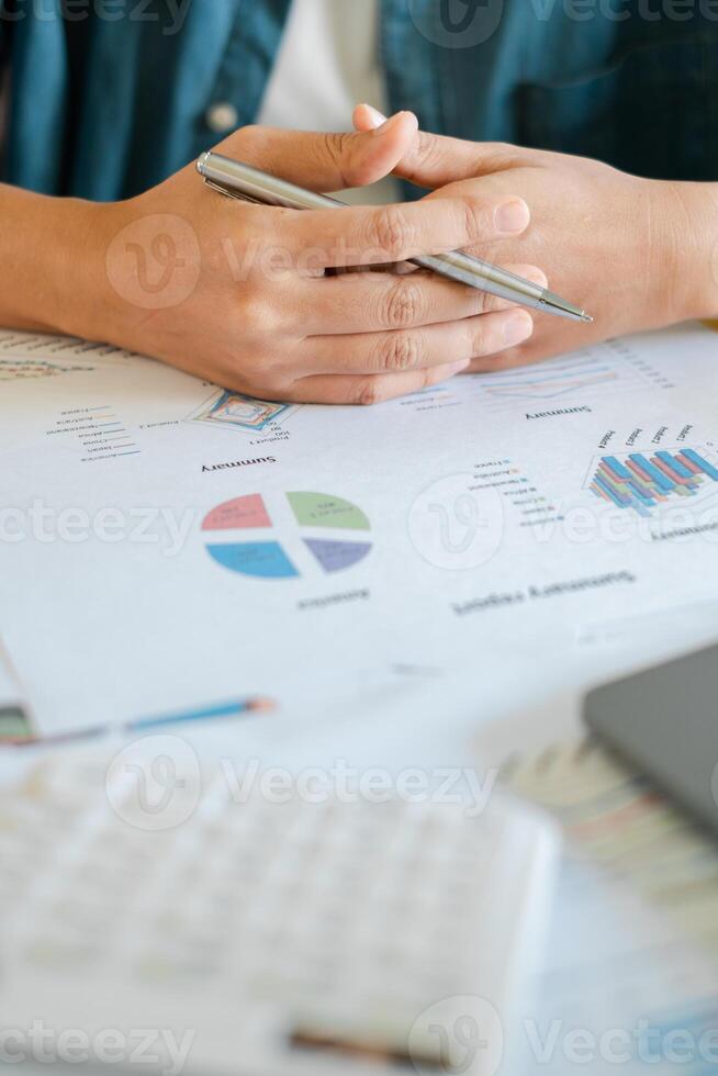Close-up of hands holding a pen over financial documents with charts and graphs, indicating business analysis and strategy. photo
