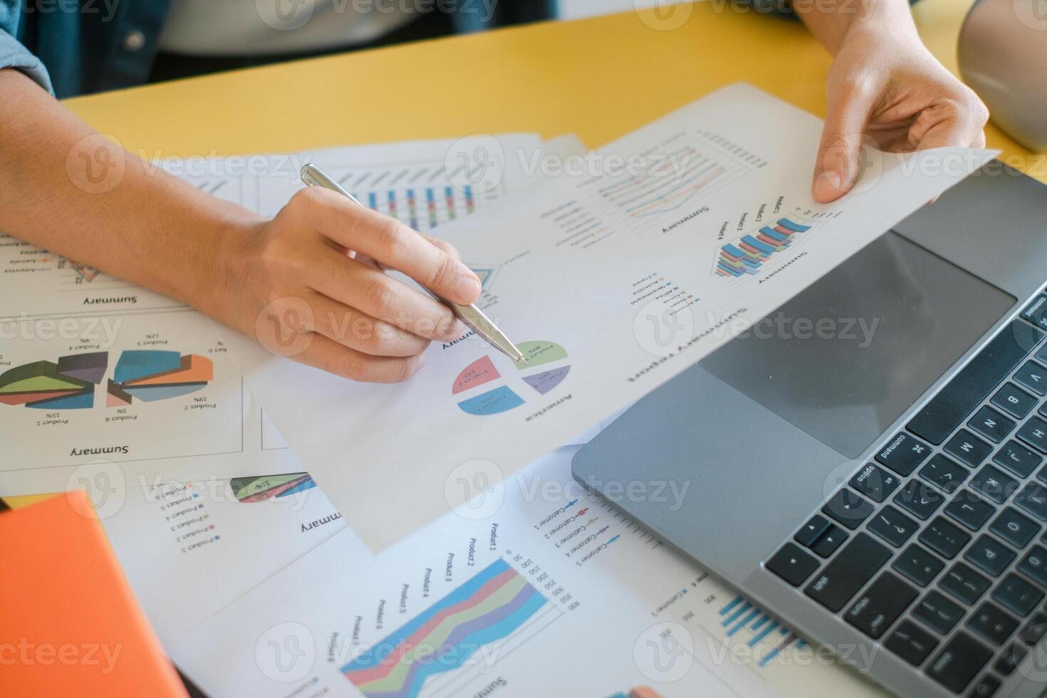 Close-up of hands reviewing financial charts and graphs on paper and laptop, showcasing business analysis and data interpretation. photo