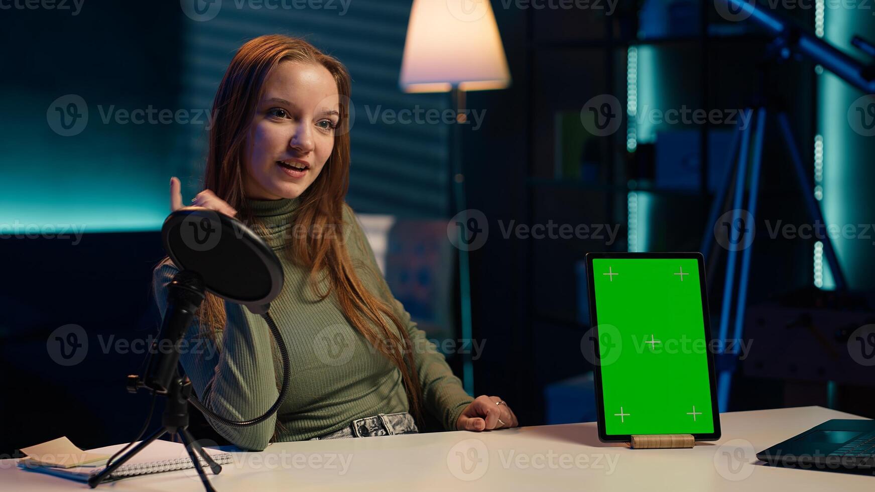 Smiling young internet star presenting green screen mockup tablet from brand sponsoring . Girl does influencer marketing by advertising chroma key isolated screen device to audience, camera A photo