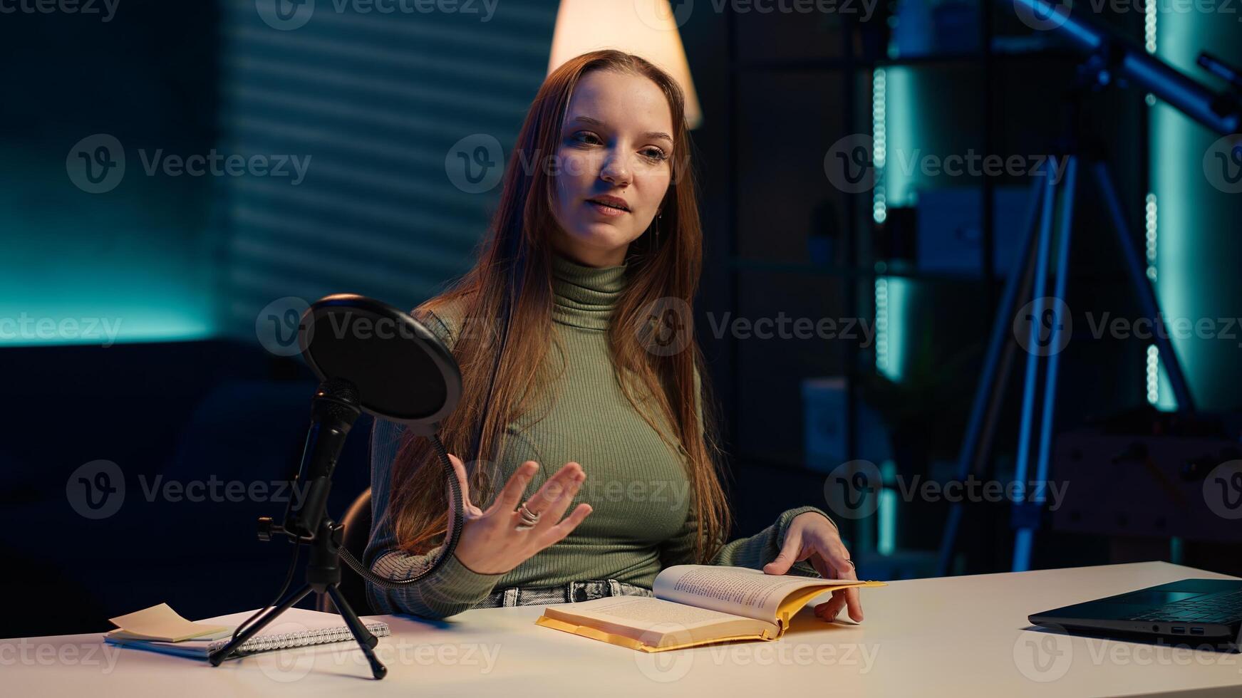 Young girl films review of book, browsing through pages, presenting synopsis to audience. Online star sponsored by publisher to show new novel release to readers, camera A photo