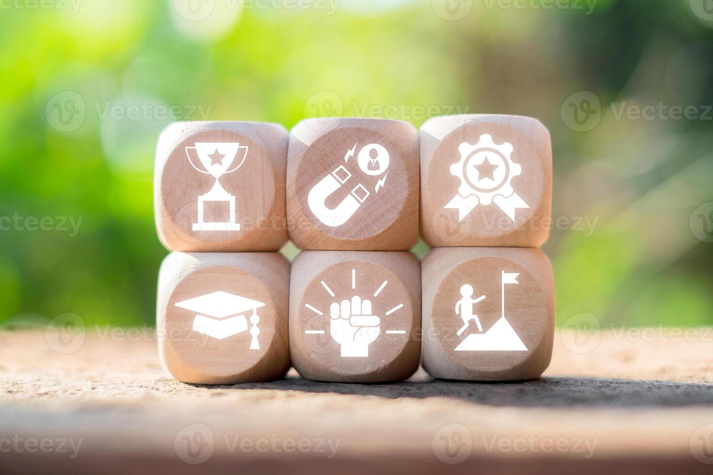 Wooden blocks with gamification icons symbolizing achievement, motivation, and success against a blurred natural background. photo