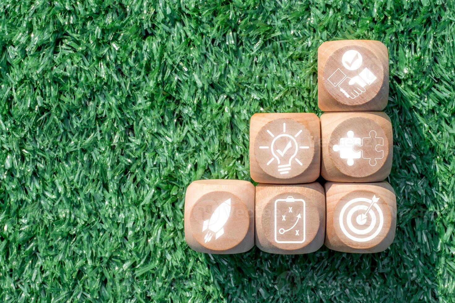 Wooden blocks on grass illustrating teamwork, innovation, and success with icons representing collaboration and strategy. photo