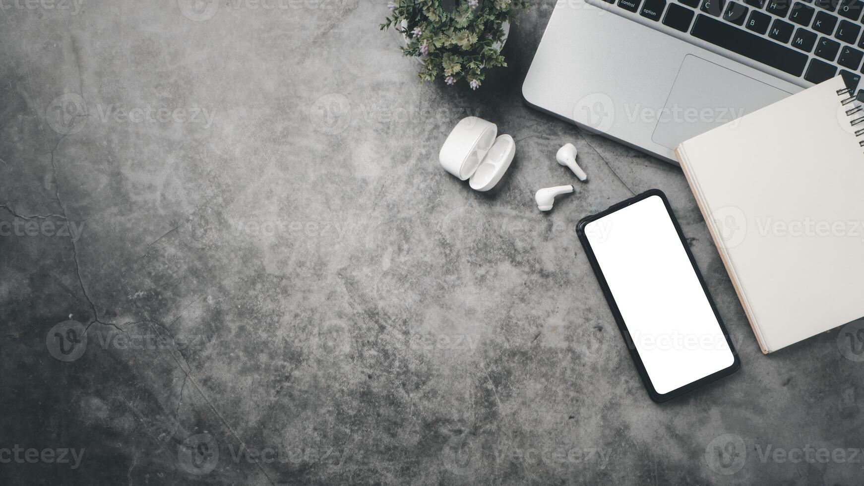 Dark office desk workspace with laptop computer, blank screen smart phone, notebook and earphone, Top view flat lay with copy space. photo