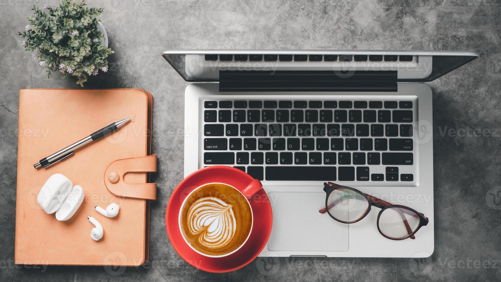 Dark office desk workspace with laptop computer, eyeglass, earphone, pen, notebook and cup of coffee, Top view flat lay with copy space. photo