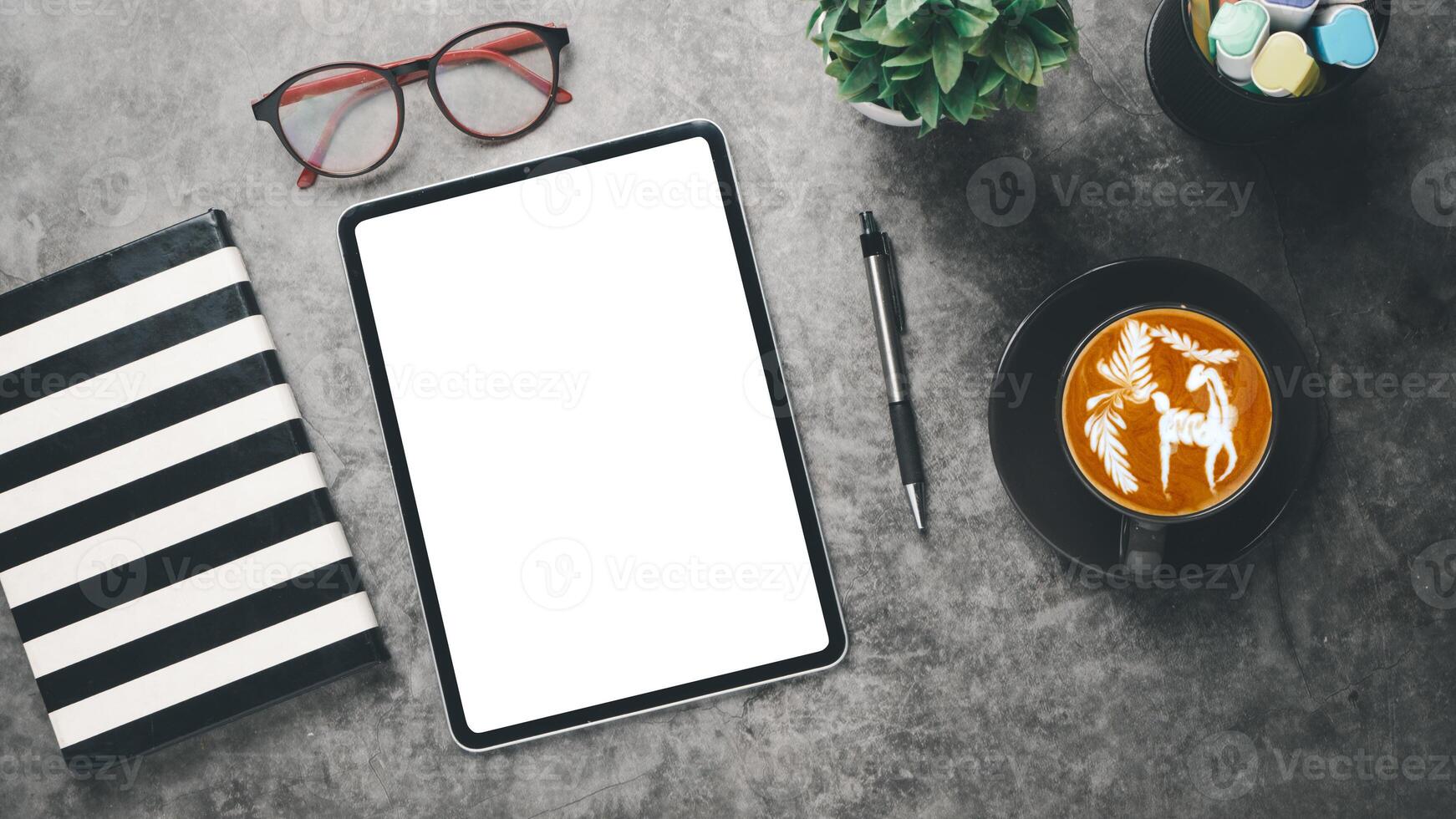 Office workplace with blank screen tablet, notebook, eyeglass, pen and cup of coffee, Top view flat lay. photo