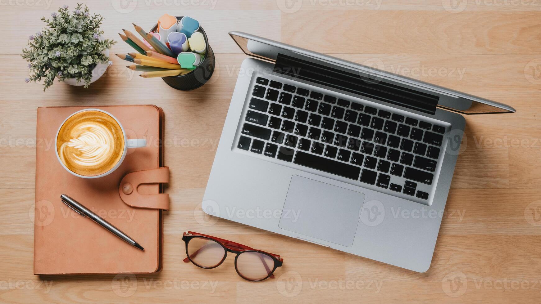 Office wooden desk workplace with laptop computer, notebook, pen, eyeglass and cup of coffee, Top view flat lay. photo