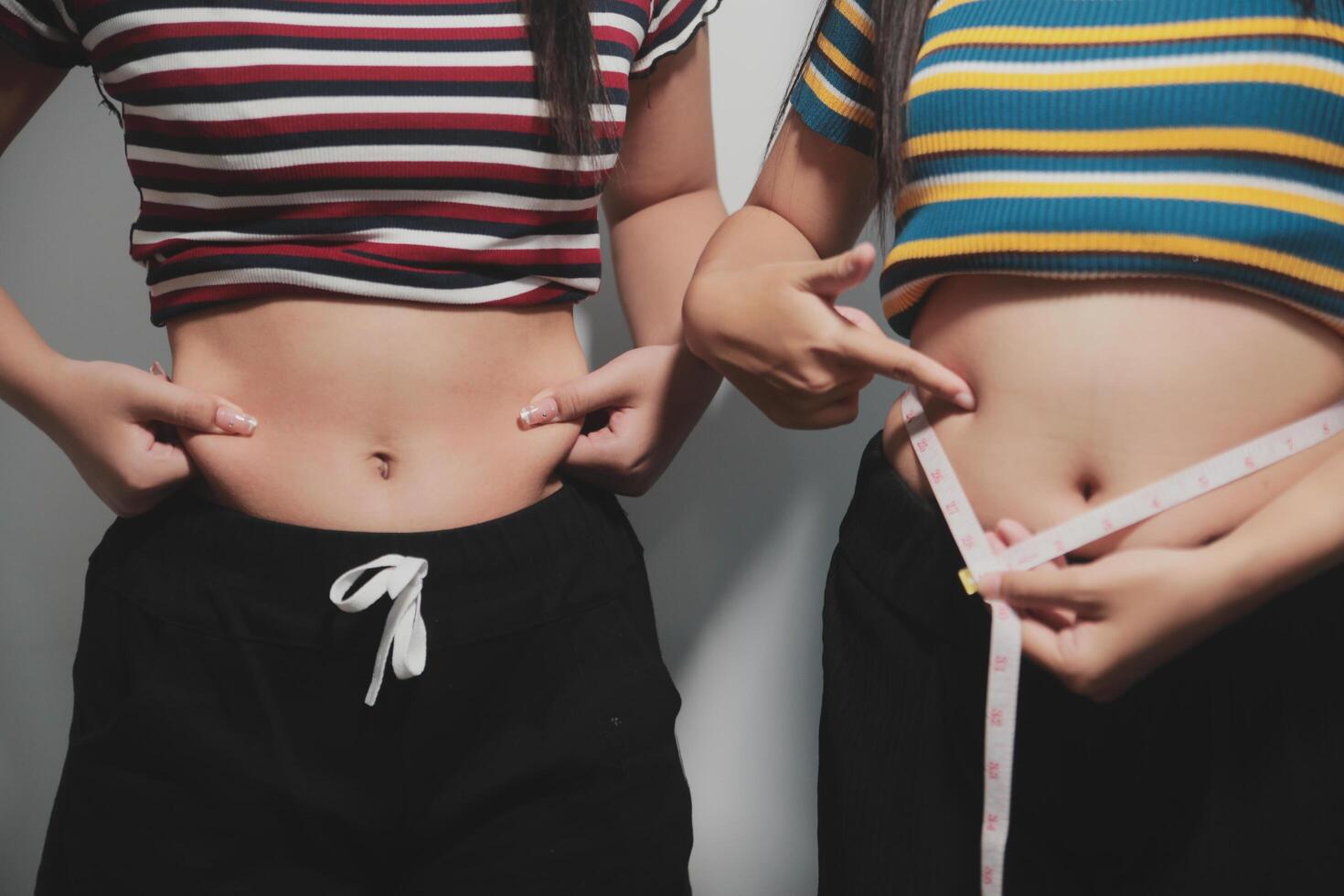 Two women measuring their stomachs with tape photo