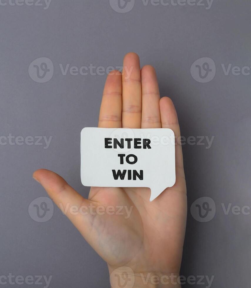 Person holds on palm white sticker with words Enter to Win photo