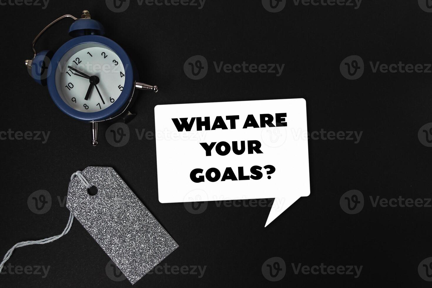 Clock is on a table with a tag that says What are your goals photo