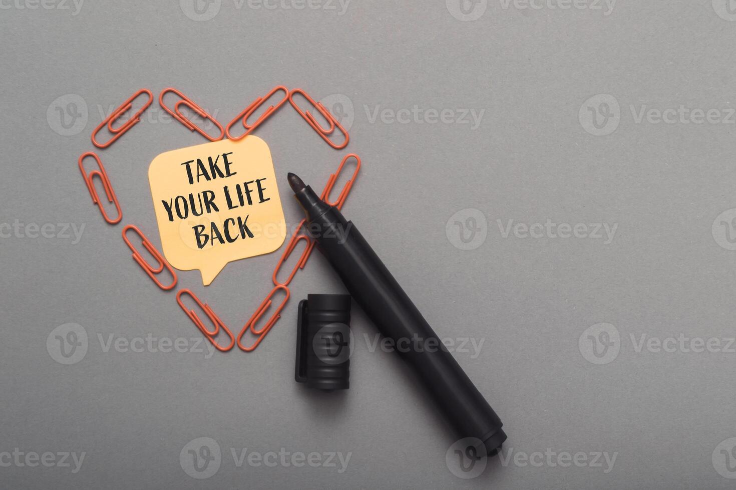 Black marker is on a gray surface with a heart shape made of paper clips photo