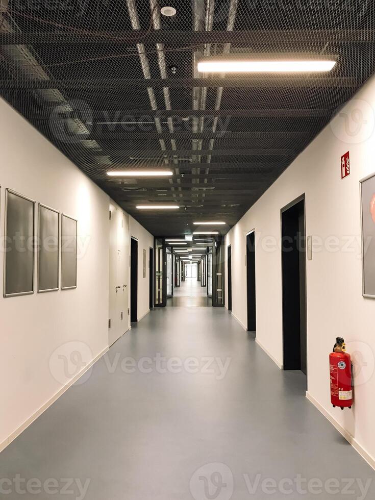 A long hallway with a red fire extinguisher on the wall photo